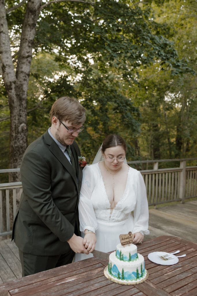 bride and groom in bar harbor maine airbnb cutting wedding cake after eloping in acadia national park