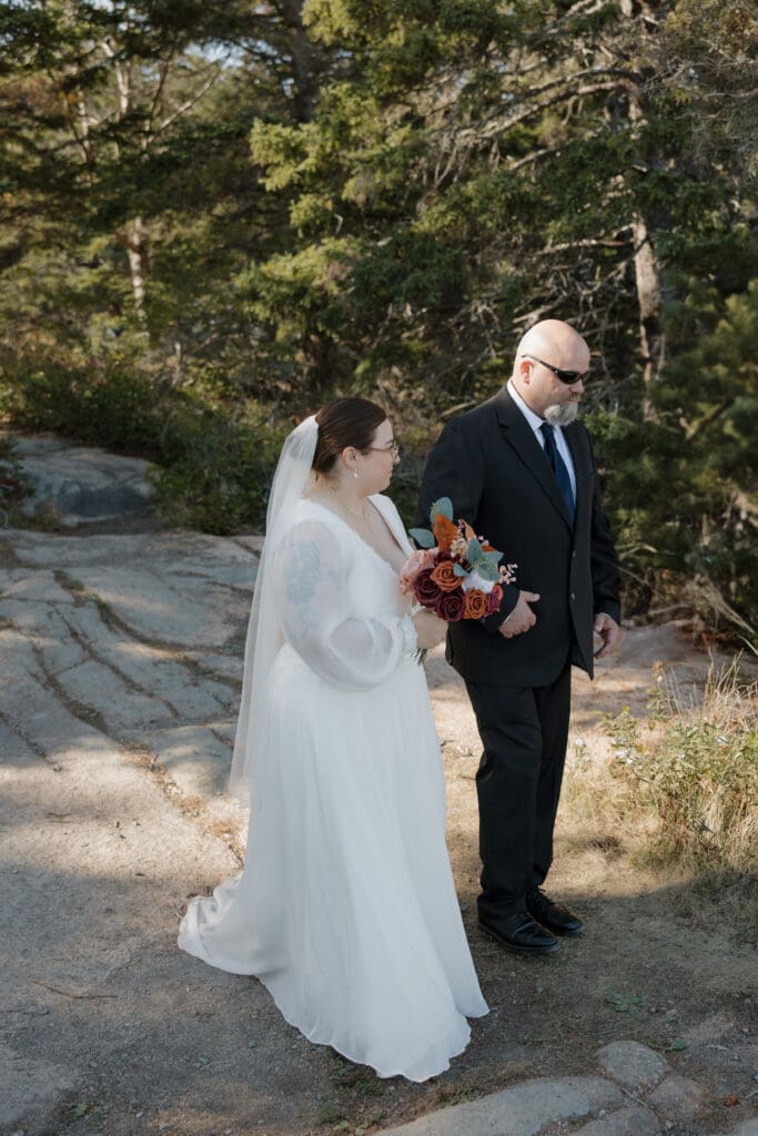 father walking bride down a trail in acadia national park to elope