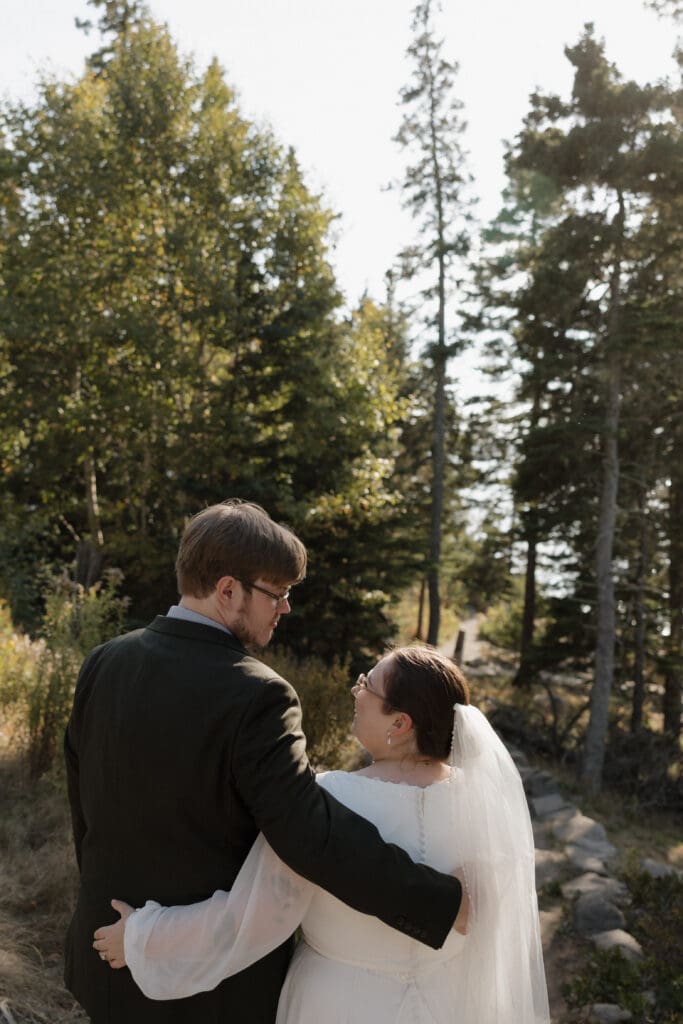 bride and groom walking down a trail in otter point acadia national park
